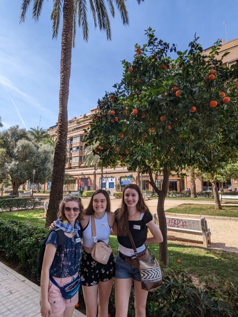 Mikayla Barnes, Alli Martin, and Meredith Thiessen stand in front of an orange tree. Photo courtesy of Mikayla Barnes.