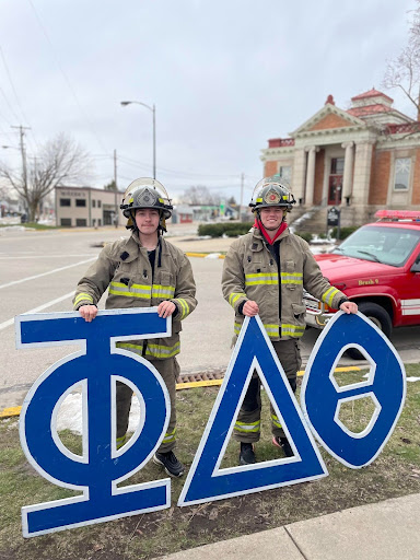 Scott Oscarson and Tyler Hebein, First-years, wearing firefighting gear for the Phi Delta Theta philanthropy event. Photo Courtesy of Miki Canak.